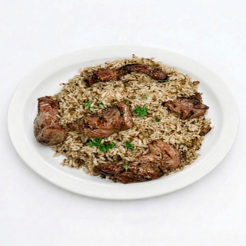 A white plate holds a serving of rice and dark meat, garnished with parsley.